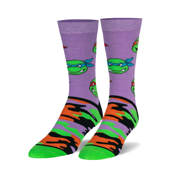 Pair of crew socks. Lavender background with repeating TMNT face pattern and orange, green, and black camouflage print on the lower part. 