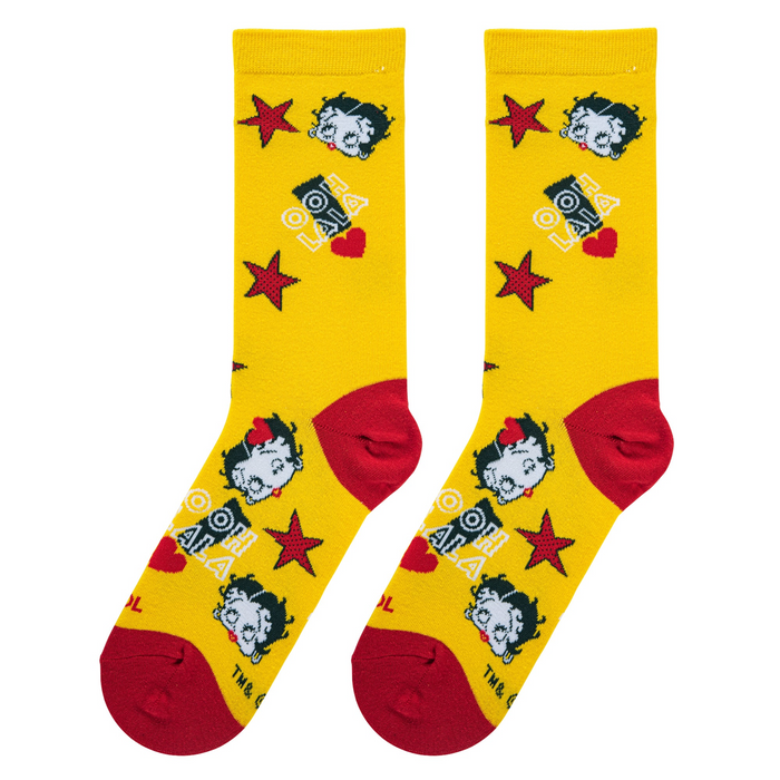 Flat lay of two yellow Betty Boop socks with red toes/heels, displaying Betty's face, stars, 