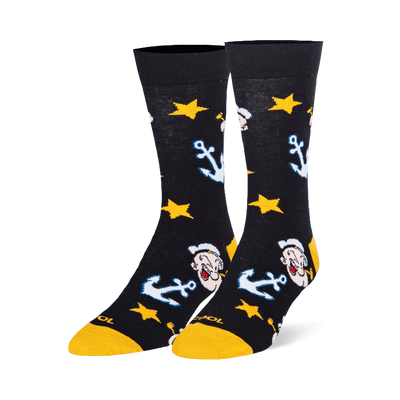 Black crew socks featuring a pattern of Popeye the Sailor Man's face, light blue anchors, and bright yellow stars.