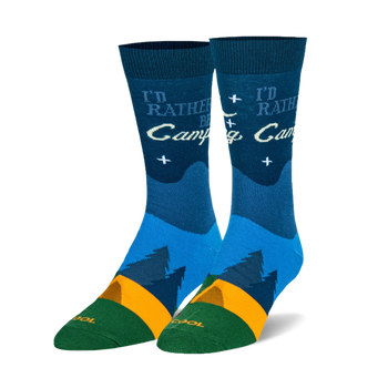 Pair of dark blue crew socks with 'I'd Rather Be Camping' text, dark blue mountain silhouettes, orange stripe, and green toe and heel.