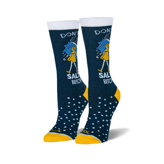Pair of women's crew socks. Dark blue with white text reading 'Don't be a Salty Bitch', yellow girl illustration under an umbrella, and white polka dots. Yellow cuffs.