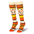 Pair of knee-high socks showing the Reese's Pieces logo, bold colored stripes, candy dots, and an orange toe box.