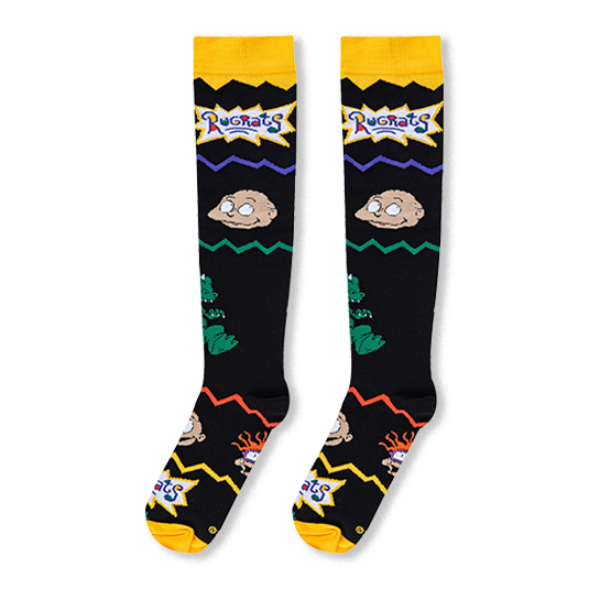 Flat lay of black knee-high socks highlighting Tommy Pickles, Reptar on the side, and the Rugrats logo near a yellow cuff.