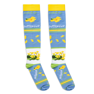 Flat lay of light blue socks showing the cursive suck it up text above scattered yellow buttercups.