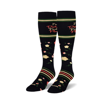 Pair of black knee-high socks with 'I'm a Delicate Fucking Flower' text. Features pink and yellow floral patterns and green, red, beige stripes.