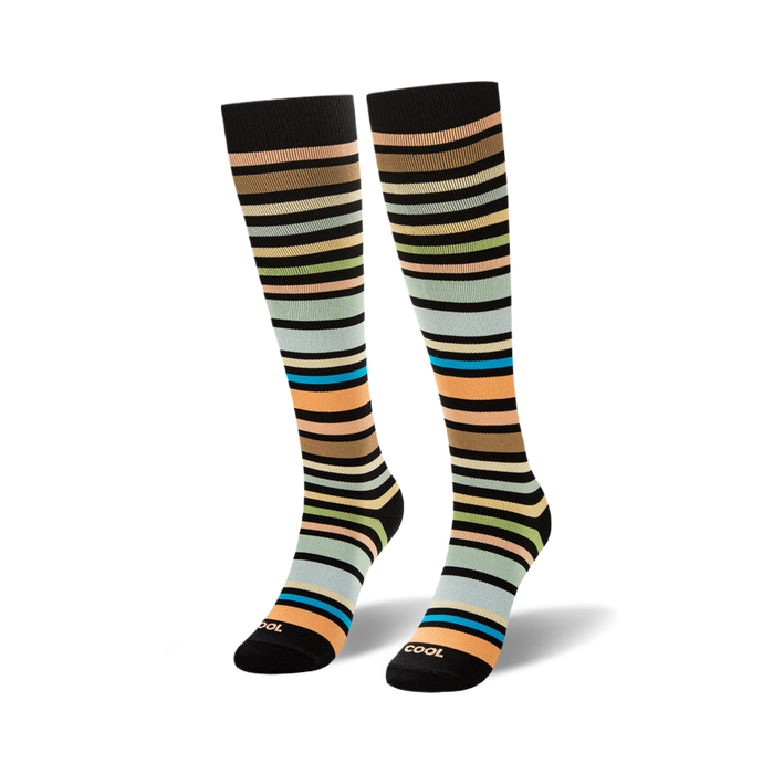 Knee-high socks featuring horizontal stripes in brown, peach, green, light blue, and bright teal on a black background.