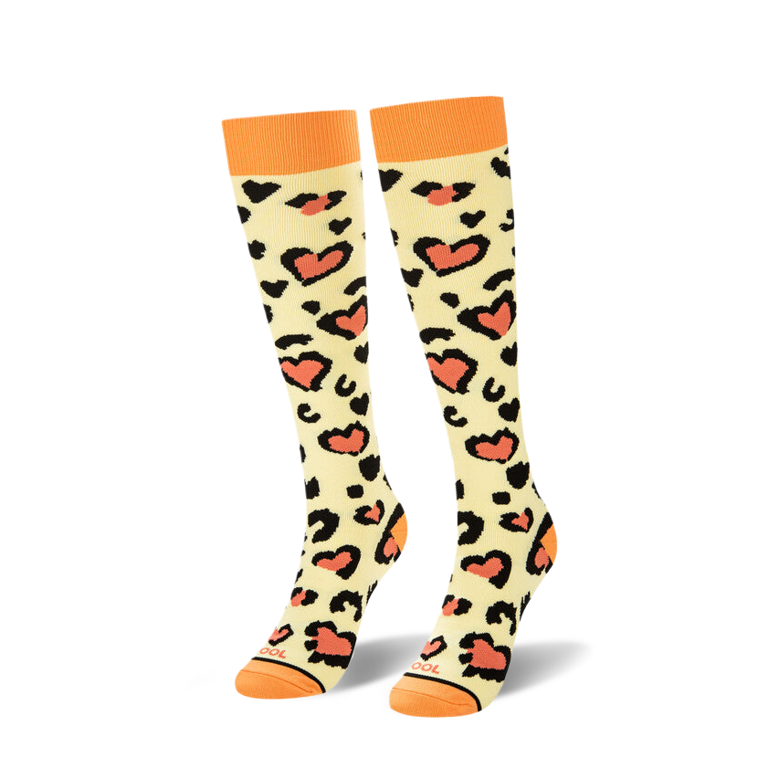 Pair of knee-high cream socks with black and coral heart-shaped leopard spots displayed on a white background.