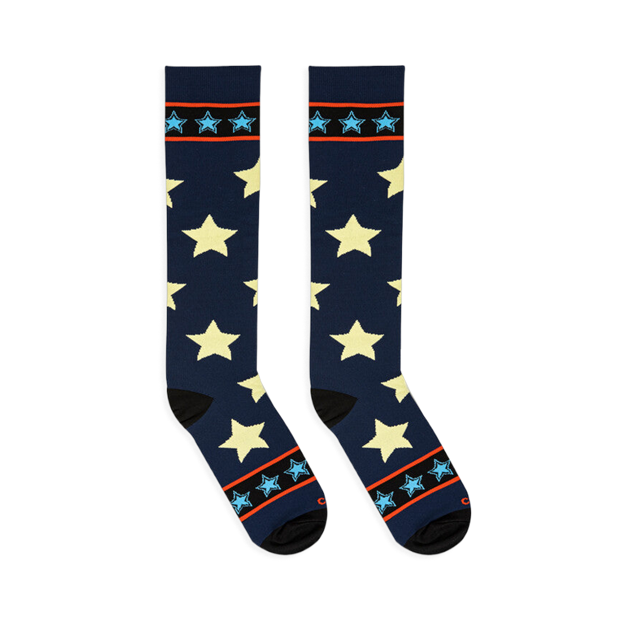 Flat lay of tall navy blue socks with pale yellow stars angled outward to display black toes and striped cuffs.
