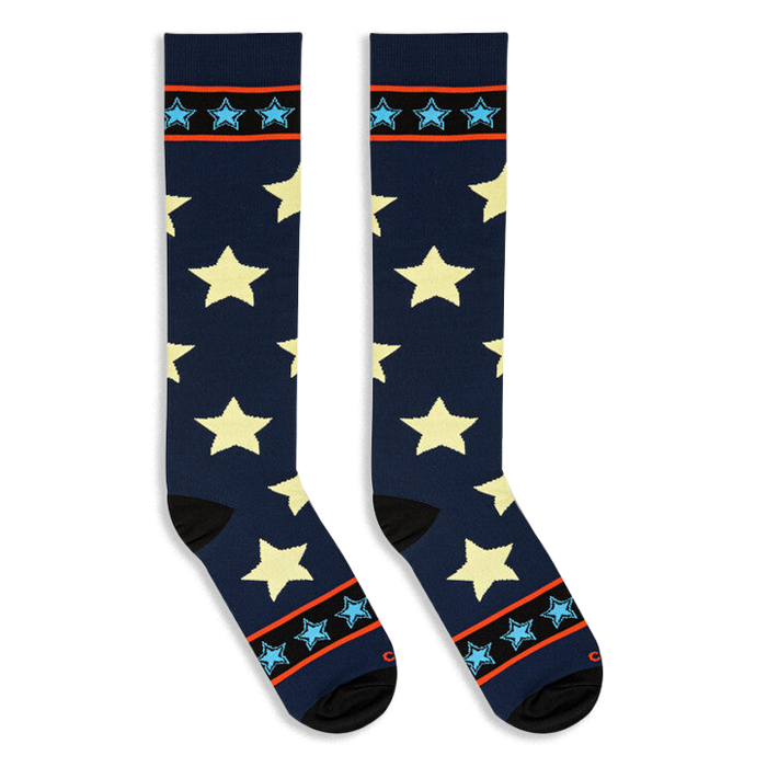 Flat lay of tall navy blue socks with pale yellow stars angled outward to display black toes and striped cuffs.