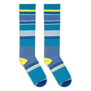 Flat lay of two blue and yellow striped knee-high socks positioned parallel to each other against a dark background.
