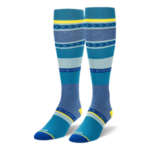 Knee-high socks featuring wide teal, navy, and heather blue stripes mixed with geometric arrow patterns and yellow accents.