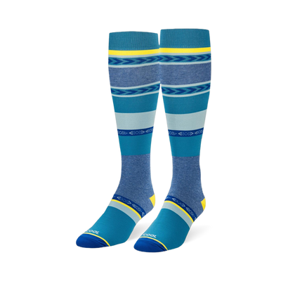 Knee-high socks featuring wide teal, navy, and heather blue stripes mixed with geometric arrow patterns and yellow accents.