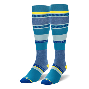 Knee-high socks featuring wide teal, navy, and heather blue stripes mixed with geometric arrow patterns and yellow accents.