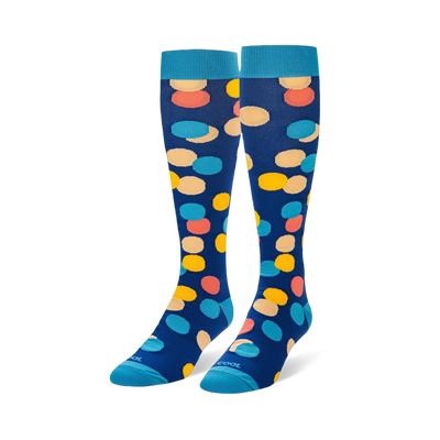 Knee-high navy blue socks with large yellow, peach, coral, and light blue polka dots, finished with bright blue cuffs.