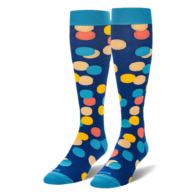 Knee-high navy blue socks with large yellow, peach, coral, and light blue polka dots, finished with bright blue cuffs.