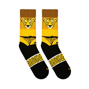 Flat lay view of two yellow and black crew socks showing a cheetah face, sunset tree silhouette, and spotted pattern band.