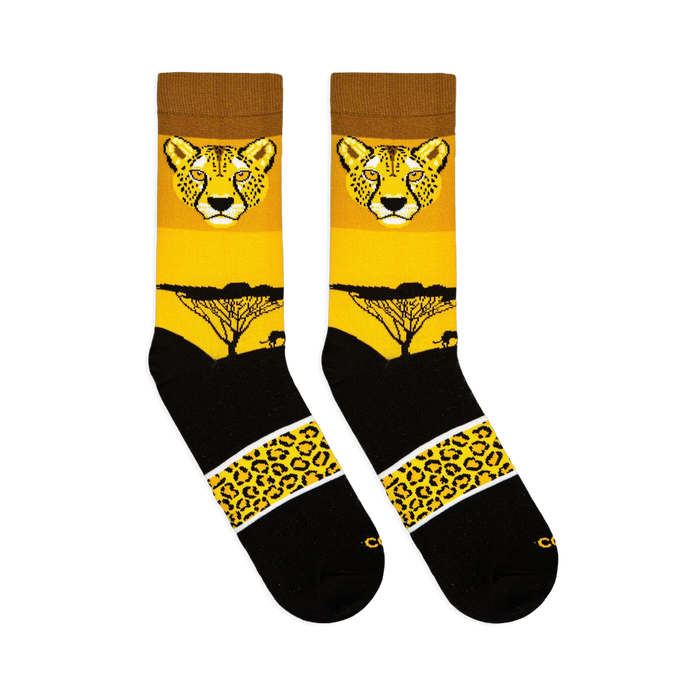 Flat lay view of two yellow and black crew socks showing a cheetah face, sunset tree silhouette, and spotted pattern band.