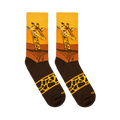Flat lay of two crew socks displaying a giraffe face over a yellow sunset, dark acacia trees, and a spotted band on the foot.