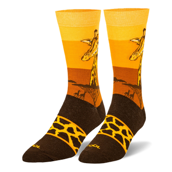 Crew socks showing a giraffe head against a yellow and orange sunset, tree silhouettes, and a brown foot with a spotted band.