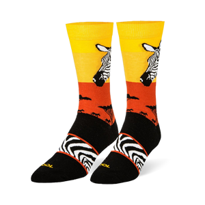 Black crew socks featuring a yellow and orange sunset, zebra head portrait, safari tree silhouettes, and an arch stripe band.