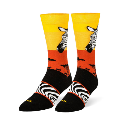 Black crew socks featuring a yellow and orange sunset, zebra head portrait, safari tree silhouettes, and an arch stripe band.