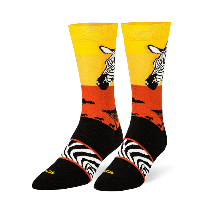Black crew socks featuring a yellow and orange sunset, zebra head portrait, safari tree silhouettes, and an arch stripe band.