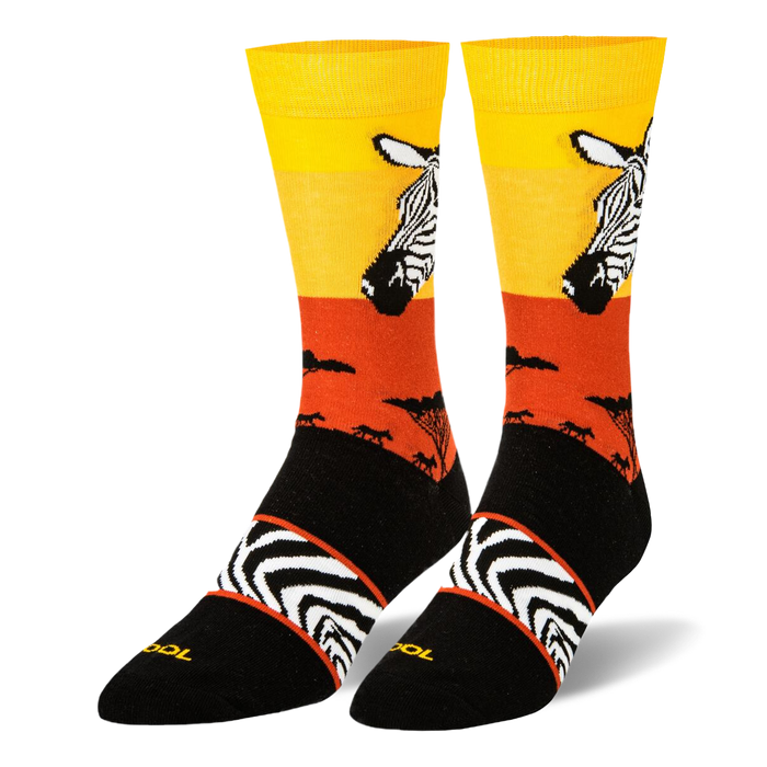 Black crew socks featuring a yellow and orange sunset, zebra head portrait, safari tree silhouettes, and an arch stripe band.