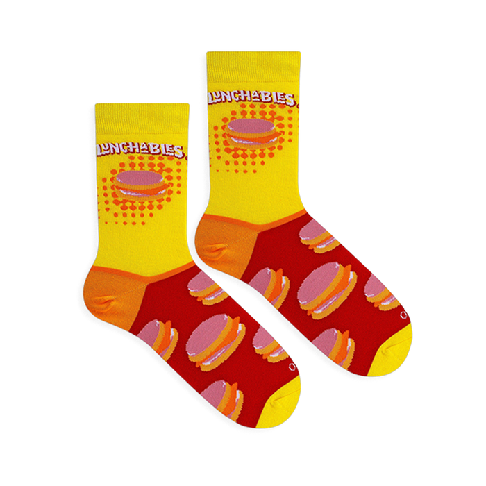 Flat lay of two Lunchables socks on a black background, showing the yellow tops, red foot pattern, and orange heels.