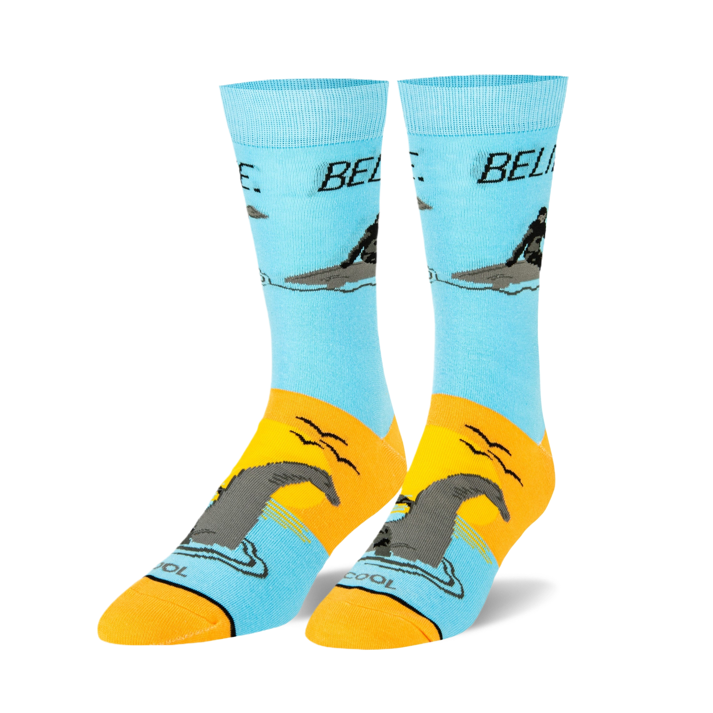 Pair of crew socks, light blue and orange, featuring a graphic of a man riding a Loch Ness Monster and the word 'BELIEVE'.
