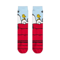 Flat lay of two crew socks side-by-side displaying Snoopy resting on a red doghouse with Woodstock under a blue sky.