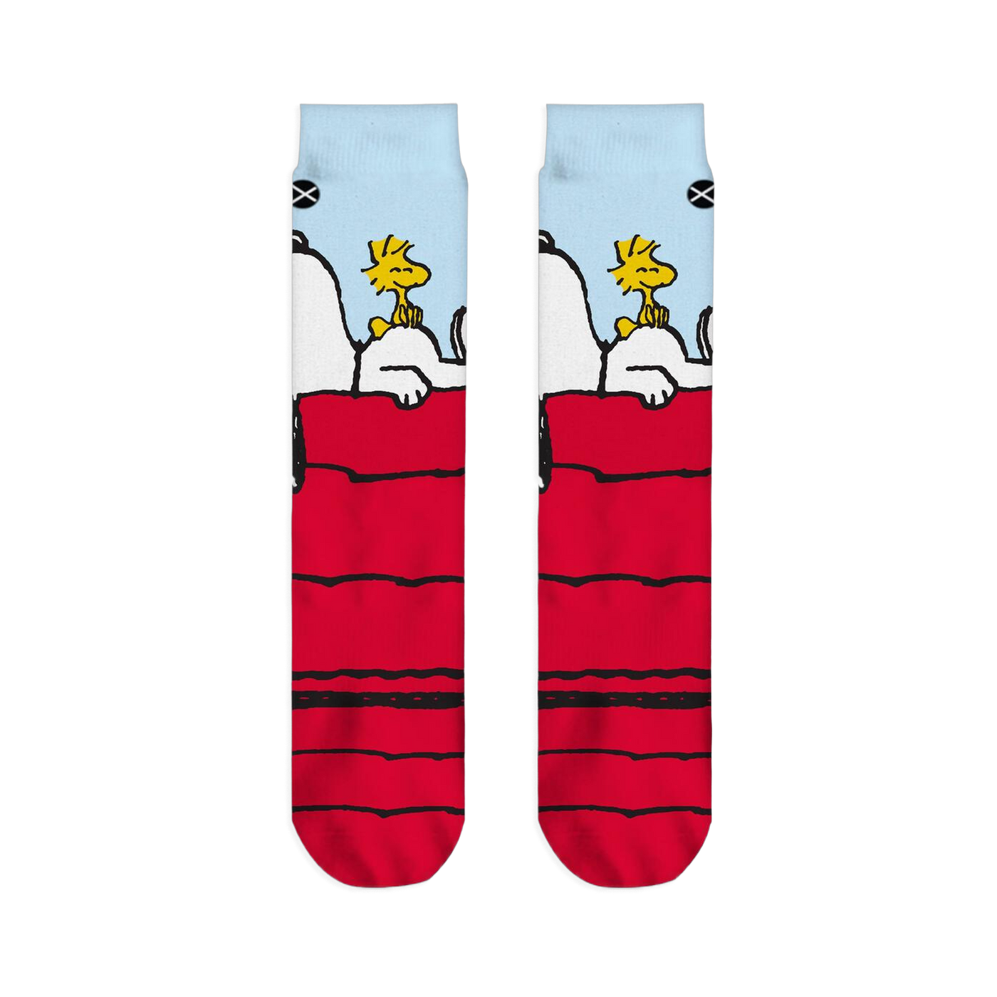 Flat lay of two crew socks side-by-side displaying Snoopy resting on a red doghouse with Woodstock under a blue sky.