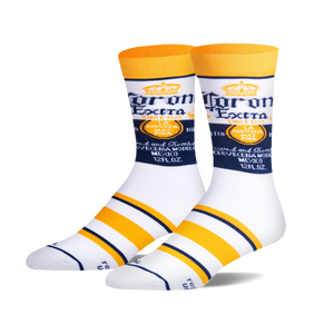 Pair of white crew socks with Corona Extra logo and yellow and navy blue stripes. 