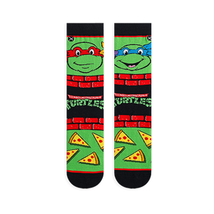 Flat lay of two TMNT socks showing Raphael in red on the left and Leonardo in blue on the right, with pizza slices below.