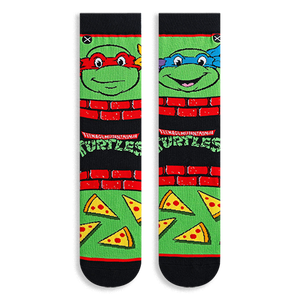 Flat lay of two TMNT socks showing Raphael in red on the left and Leonardo in blue on the right, with pizza slices below.