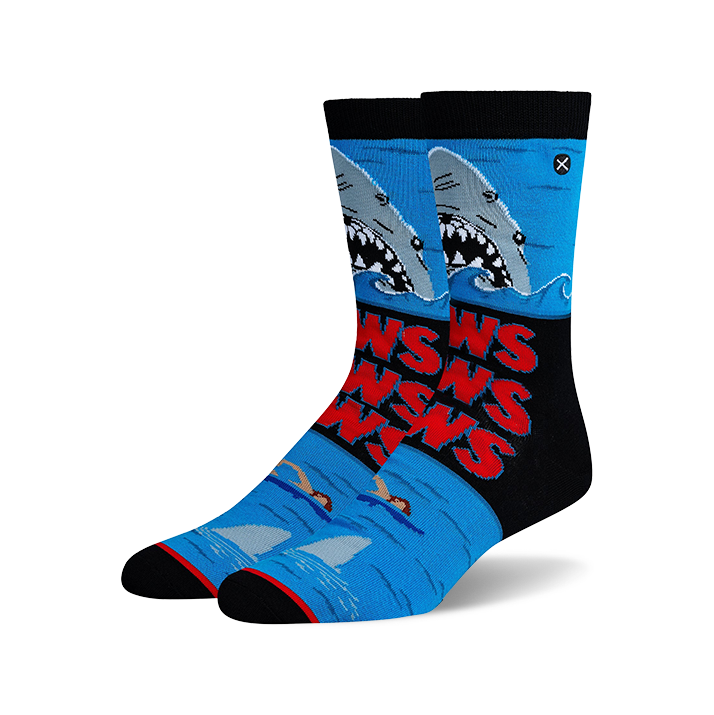 Pair of Jaws-themed crew socks. Blue, black, and red design features the Jaws movie poster with sharks and swimmers.