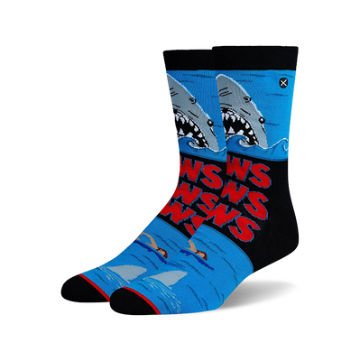 Blue crew socks with a Jaws movie design: gray sharks, red "JAWS" text, swimmers, and black accents.