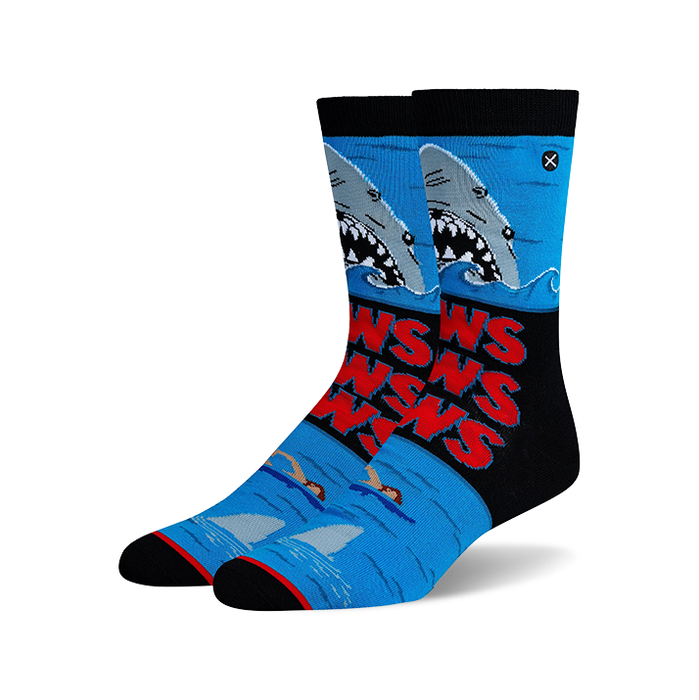 Pair of Jaws-themed crew socks. Blue, black, and red design features the Jaws movie poster with sharks and swimmers.