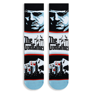 Flat lay of Godfather crew socks displaying a blue character portrait, The Godfather logo, and playing cards with a skyline.