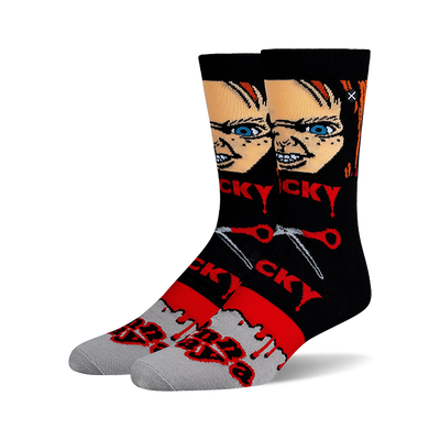 Pair of crew socks with black tops, Chucky doll face, red "CHUCKY" text, crossed red scissors, and blood drips.