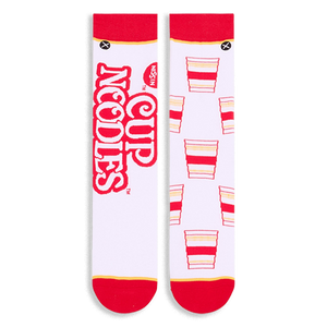 Flat lay of white socks side-by-side. Left sock shows large red Cup Noodles text, right sock shows repeating noodle cups.