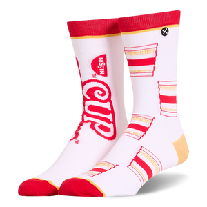 White crew socks featuring a mismatched design with a large red Cup Noodles logo on one and a pattern of cups on the other.