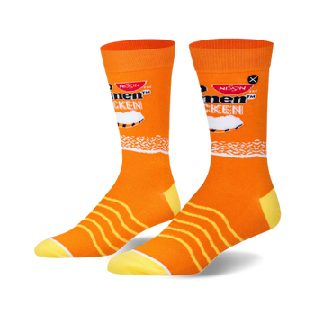 Pair of bright orange crew socks featuring Top Ramen Chicken graphics, including the Nissin logo, a chicken shape, and white noodle patterns. Yellow heels and toes.