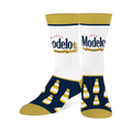 Two crew socks with white calves featuring the Modelo beer logo, navy blue feet with yellow-capped beer bottles, and gold toes, heels, and cuffs.