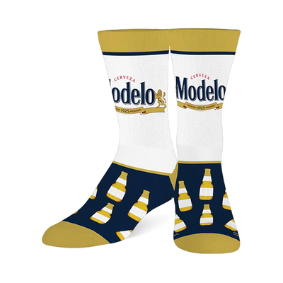 Two crew socks with white calves featuring the Modelo beer logo, navy blue feet with yellow-capped beer bottles, and gold toes, heels, and cuffs.