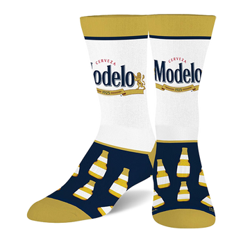 Two crew socks with white calves featuring the Modelo beer logo, navy blue feet with yellow-capped beer bottles, and gold toes, heels, and cuffs.