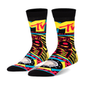 A pair of black crew socks with a vibrant 90s-inspired design.  The socks feature the MTV logo, tiger stripes, and bright yellow, red, and teal accents.