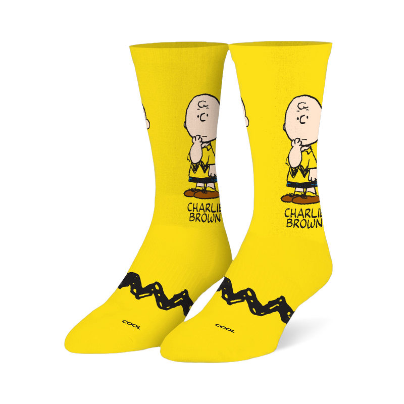 Bright yellow crew socks featuring a pensive Charlie Brown illustration on the leg and his signature black zigzag stripe.