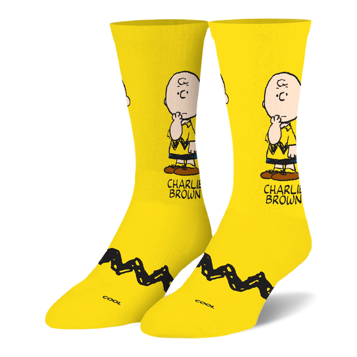 Bright yellow crew socks featuring a pensive Charlie Brown illustration on the leg and his signature black zigzag stripe.