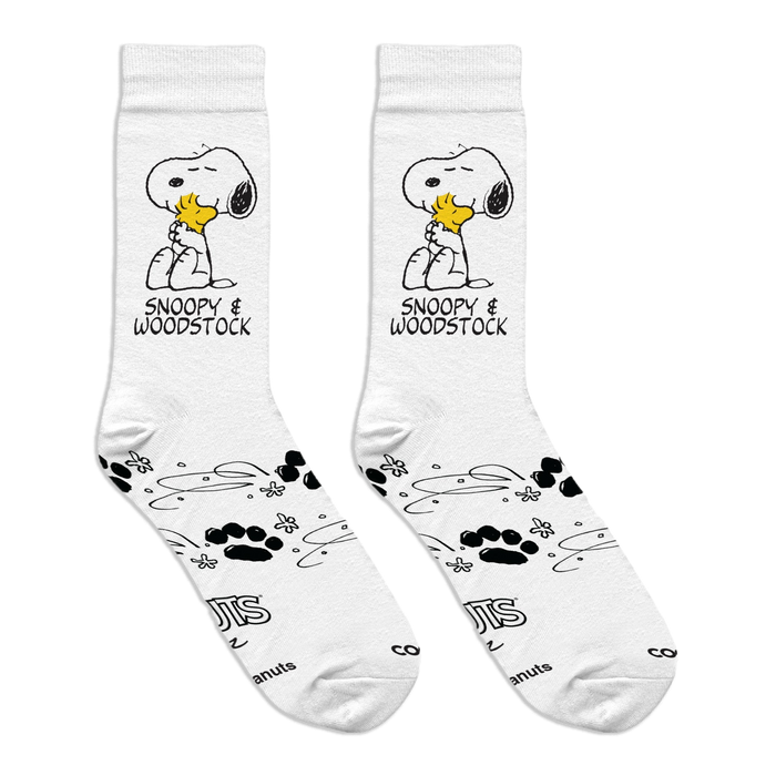 Flat lay of white crew socks showing Snoopy hugging Woodstock, paired with paw prints, swirls, and Peanuts copyright text.