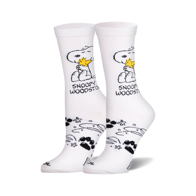 Pair of white crew socks showing Snoopy holding Woodstock, with black paw prints and star shapes on the ankle.